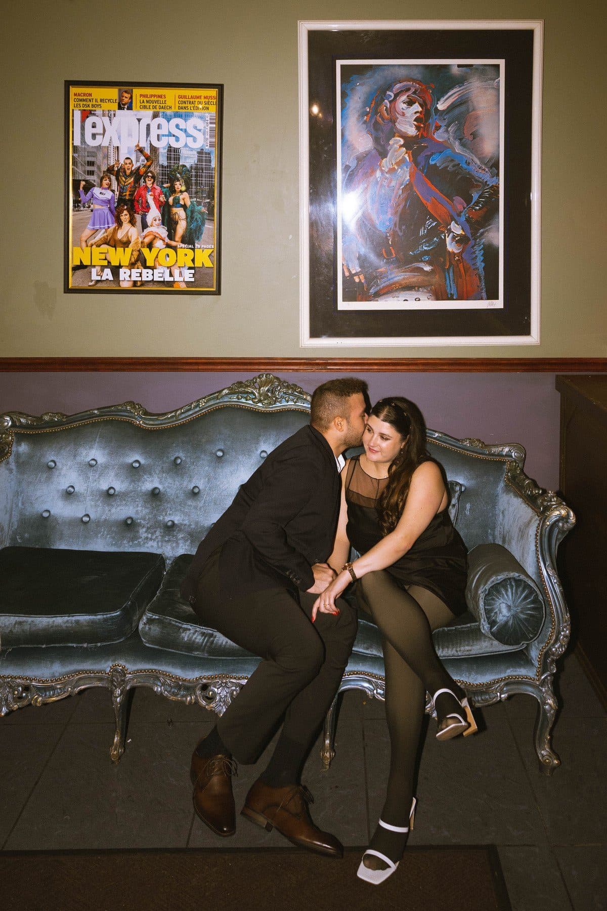 Rodolf and Lexie sitting together on a blue couch after the proposal